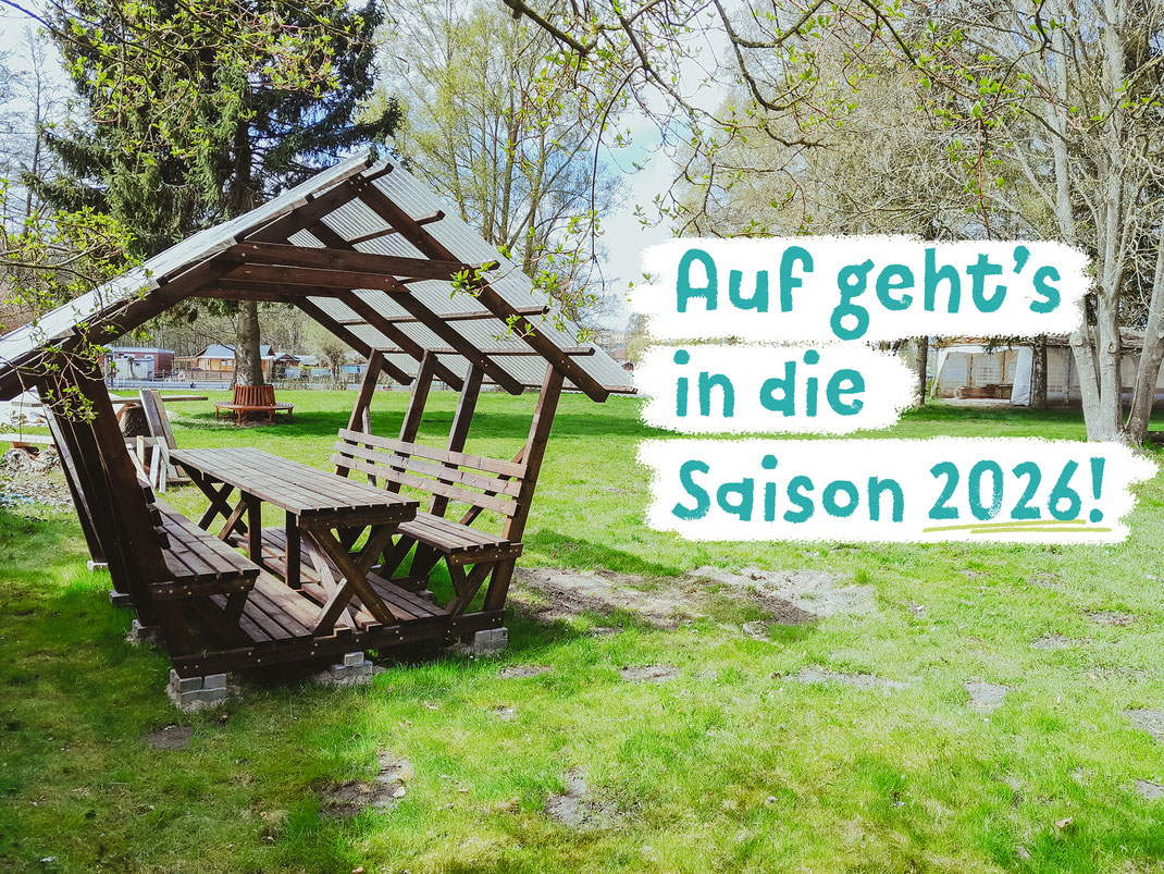 Blick auf eine Wiese mit überdachter Sitzgelegenheit im Flussbad