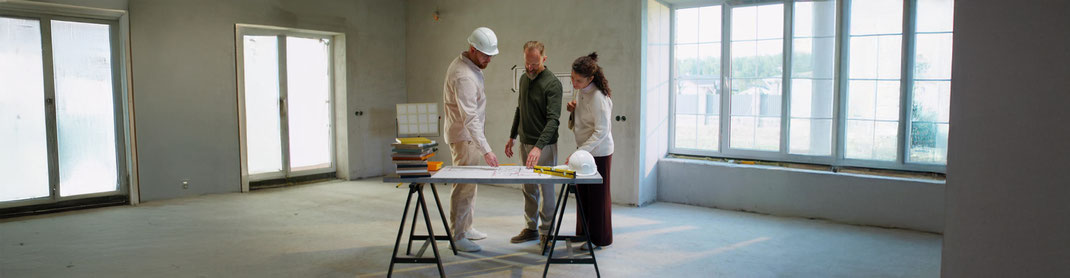 Bauleiter mit Plänen auf Baustelle bei Tragwerksprüfung in Sanierungsobjekt