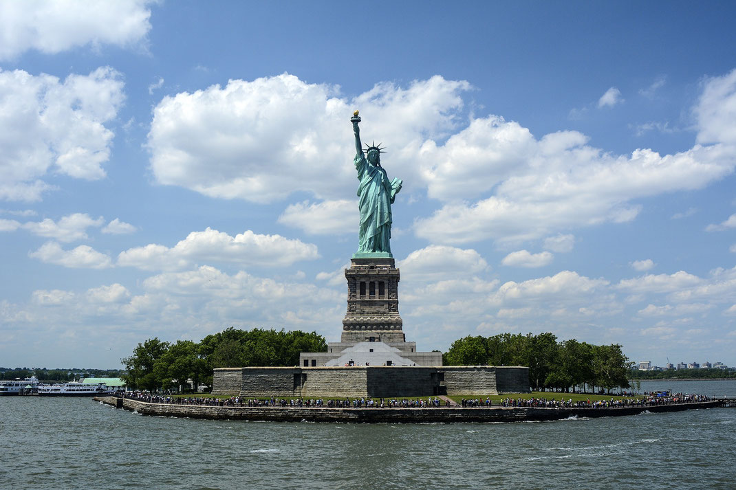 Die Geschichte der Freiheitsstatue in New York: Blick von der Fähre auf Liberty Island und die Freiheitsstatue.