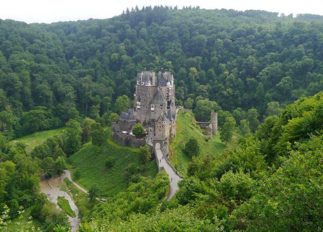 Burg Eltz, umflossen vom Elzbach, auf einem 70 m hohen Felssporn in einem Nebental der Mosel stehend