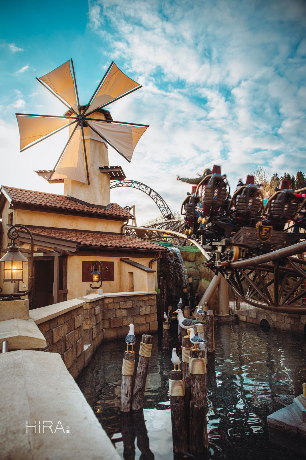 Roller Coaster Helios with it's warm-colored theming, a windmill and seagulls over a small pool