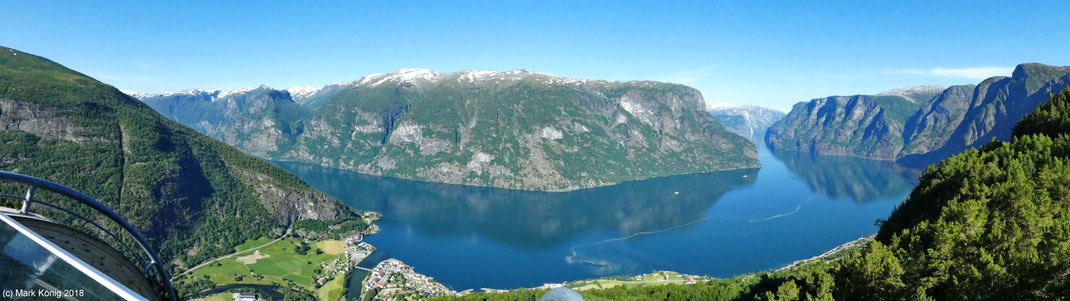 Panorama photo from a 600 meter high platform over snow-topped mountains directly located at mirroring surface of Aurlandsfjord