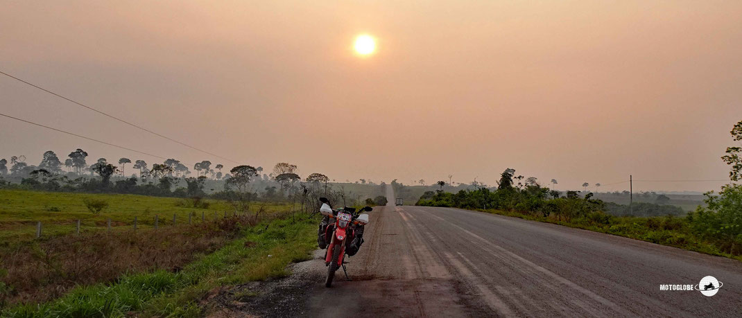 Brasilien mit dem Motorrad, Morgenstimmung. Teerstrasse, rote Sonne, diffuses Licht durch Morgennebel. Dschungel, Honda CRF 300L