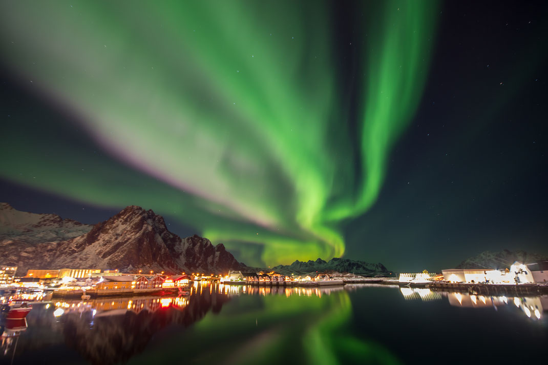 Der Hafen von Svolvær auf den Lofoten. Sonnenwind wirkt auf die Magnetfeldlinien ein und lässt das Polarlicht tanzen. Aus Bändern werden Spiralen.
