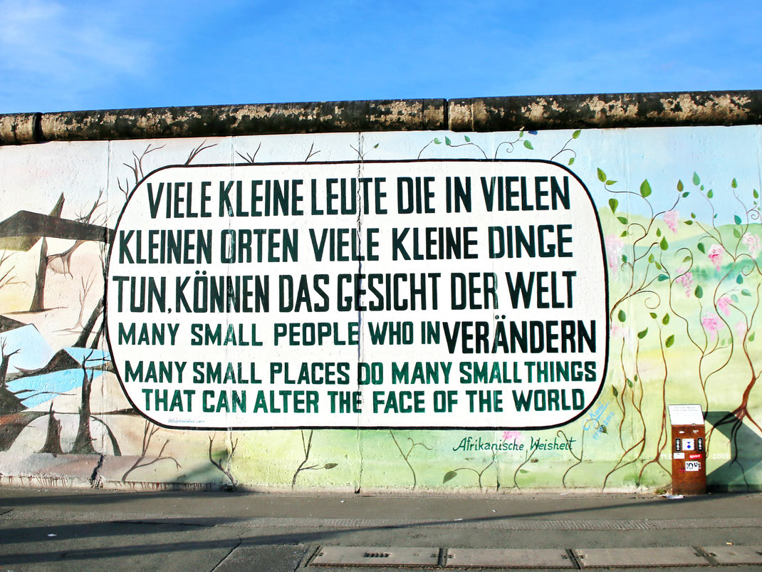 Viele kleine Leute die in vielen kleinen Orten viele kleine Dinge tun, können das Gesicht der Welt verändern. Many small people who in many small places do many small things that can alter the face of the world. Text written in a bubble on Berlin Wall. 