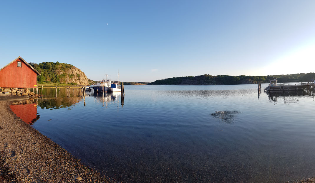 Seepromenade mit rotem Holzhaus links im Hintergrund und Boote