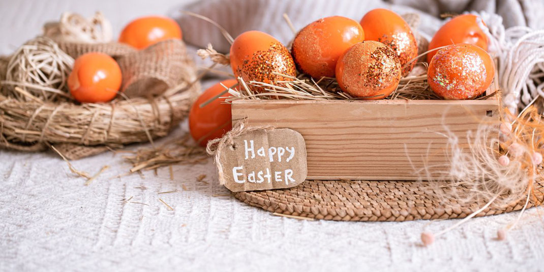 Holzkiste mit dekorierten Ostereiern und Schild mit der Aufschrift Happy Easter