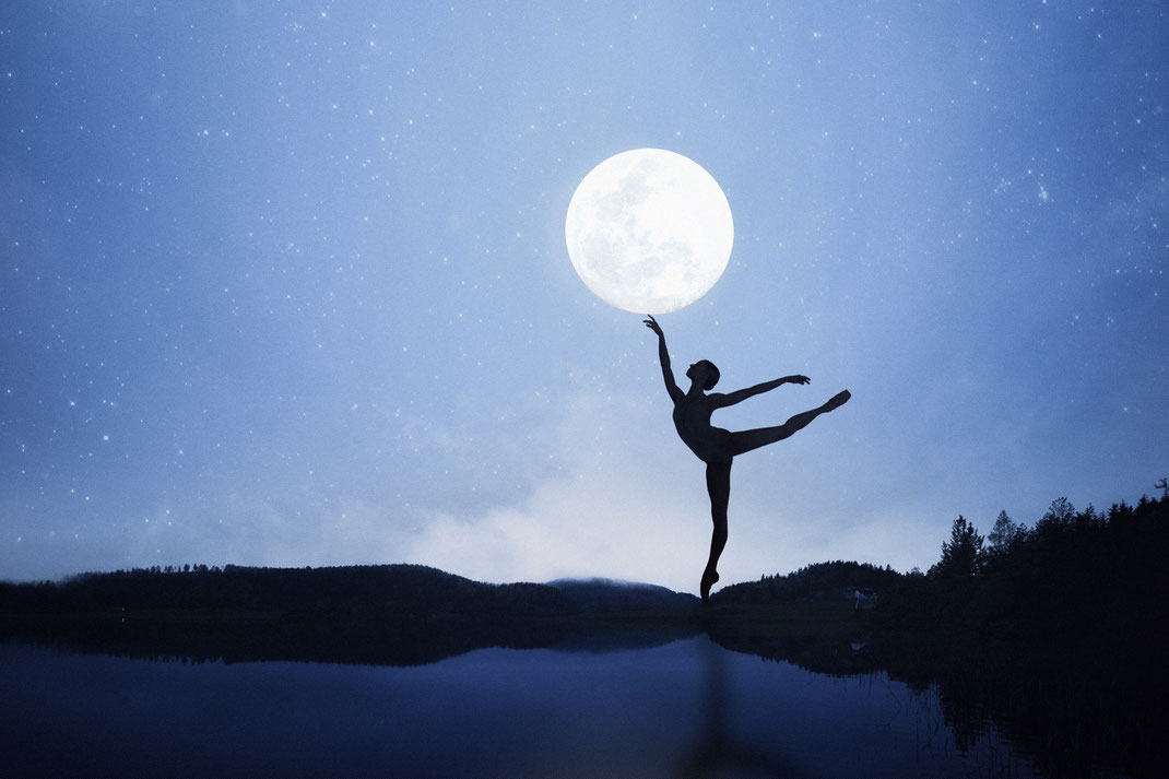 Silhouette einer Ballerina in nächtlicher Landschaft, die scheinbar den Vollmond berührt – poetische Szene mit Sternenhimmel und Spiegelung im Wasser.