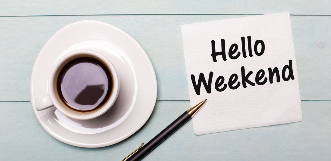 Weiße Kaffeetasse auf Unterteller mit goldenem Kugelschreiber und Serviette, auf der „Hello Weekend“ steht – stilvoller Start ins Wochenende.