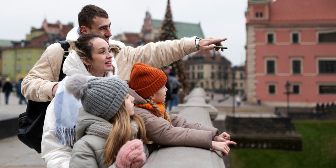 Familie mit zwei Kindern schaut von einer Brücke auf die Stadt und Sehenswürdigkeiten.