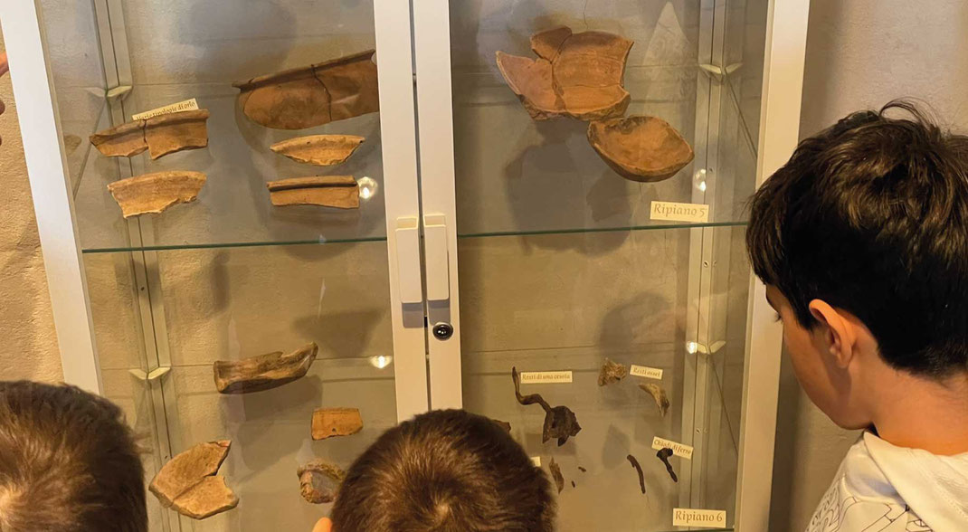 Bambini che osservano reperti archeologici in una vetrina museale durante una visita educativa