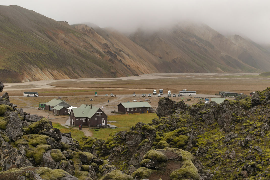 Landmannalaugar in Autumn - mountain huts behind lava and moss, with mountains behind in the fog