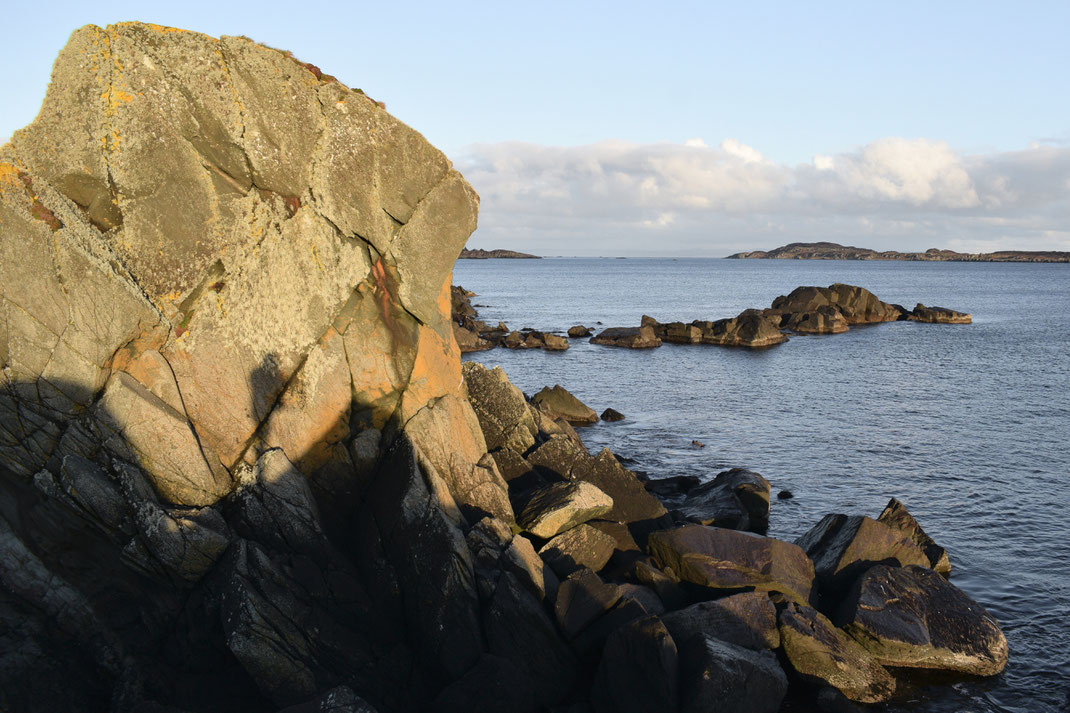 the shadow of a person standing on a rock, by the sea