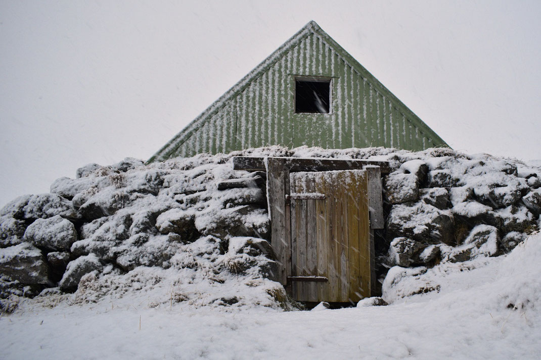 Landmannalaugar in winter. Small mountain hut with green corrigated metal and stone wall, with wooden door