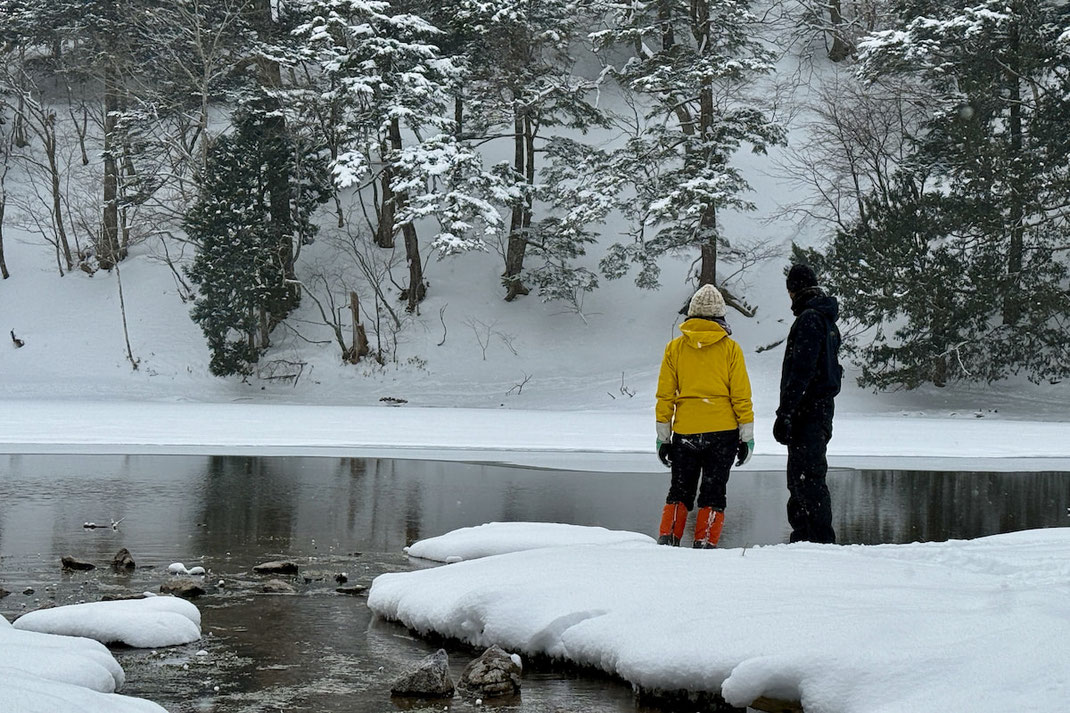 雪の奥日光の湖畔で言葉を交わさず同じ景色を眺める二人のよる森参加者。