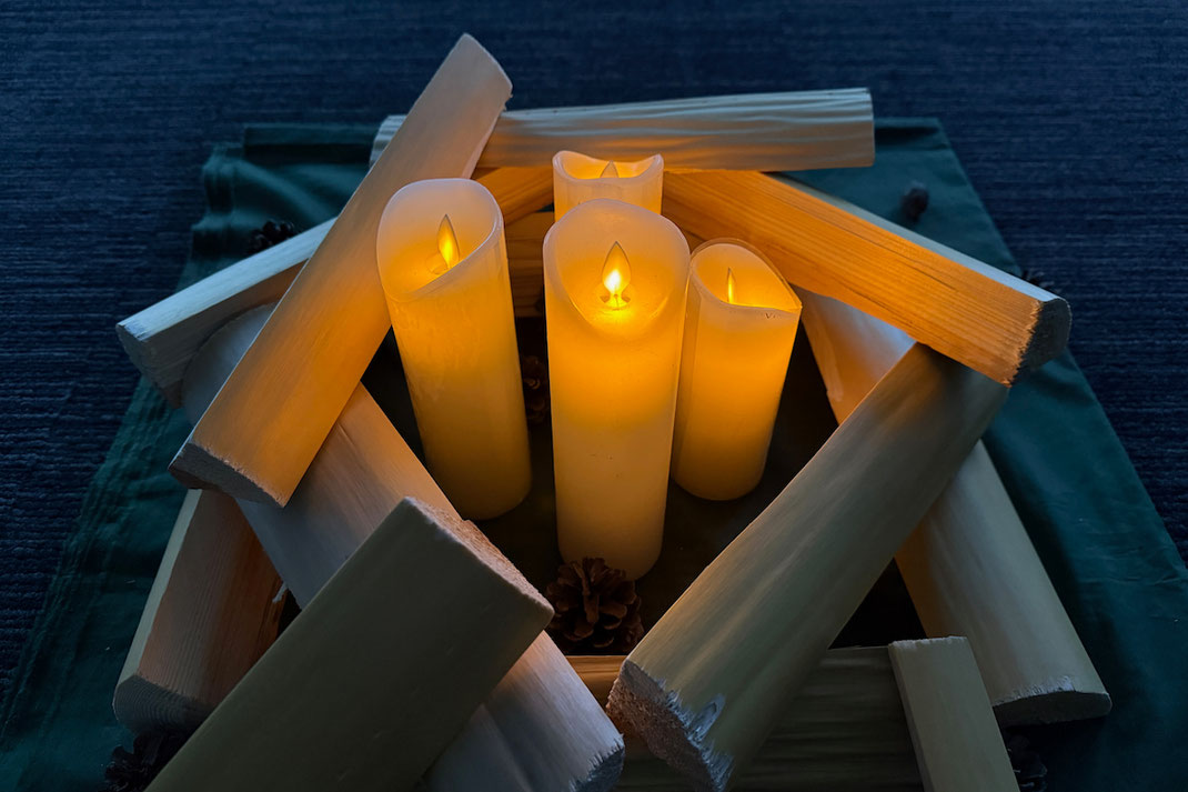 室内での五感ワークのために灯された、薪に囲まれた蝋燭の柔らかな光