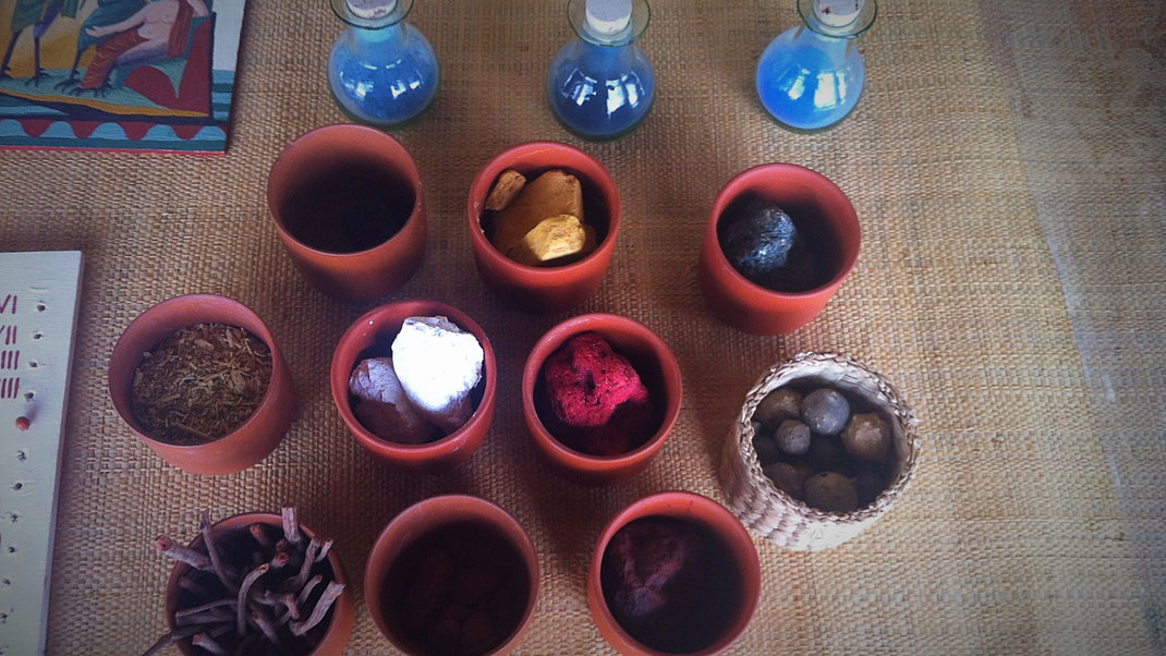 Up (in bottles, from the left): Azurite, indigo from wode, egyptian blue. First row (pots): Azurite, gold ocre, green earth. Middle row: Reseda, chalk, cinnabar, galls (basket). Lower row: Krapp roots, ruddle, red ocre.