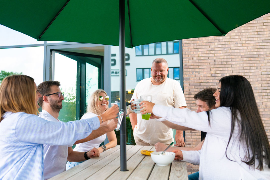 Mitarbeiter stoßen am Tisch mit Kaffee an