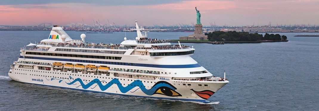 Foto der AIDAaura bei der Einfahrt nach New York vorbei an der Freiheitsstatue, ergänzt um Hinweise zu Weltreisen und Weltreise‑Routen ab Hamburg von AIDA, Cunard und Phoenix Reisen; präsentiert vom Reisebüro Reiselotsen Hamburg‑HafenCity