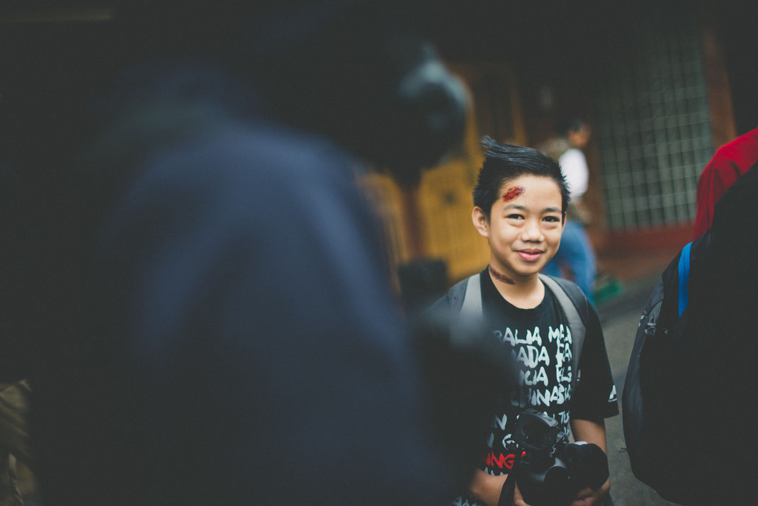 an asian boy with painted wounds looking into camera