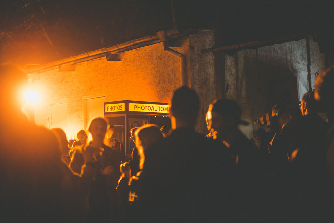 a photo booth standing in a crowd illuminated by backlight