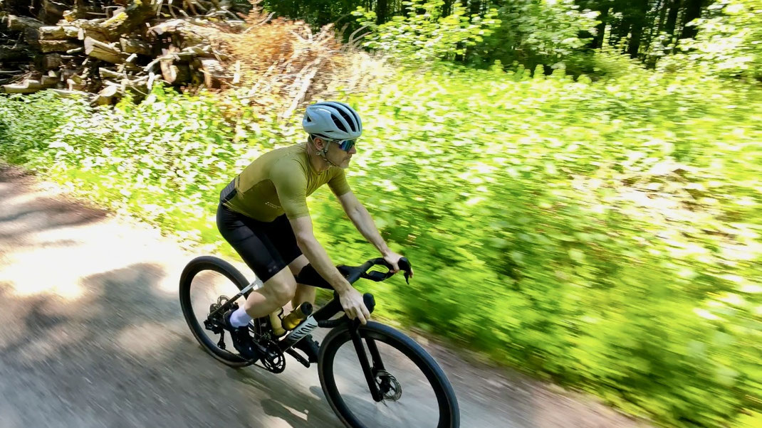 Gravelbike-Fahrer auf einem Schotterweg im Wald des Freiamts bei sommerlichen Bedingungen.