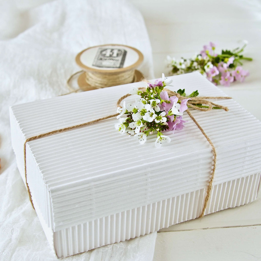 Weisse Geschenk Schachtel mit Schleife und einem kleinen Blumensträusschen