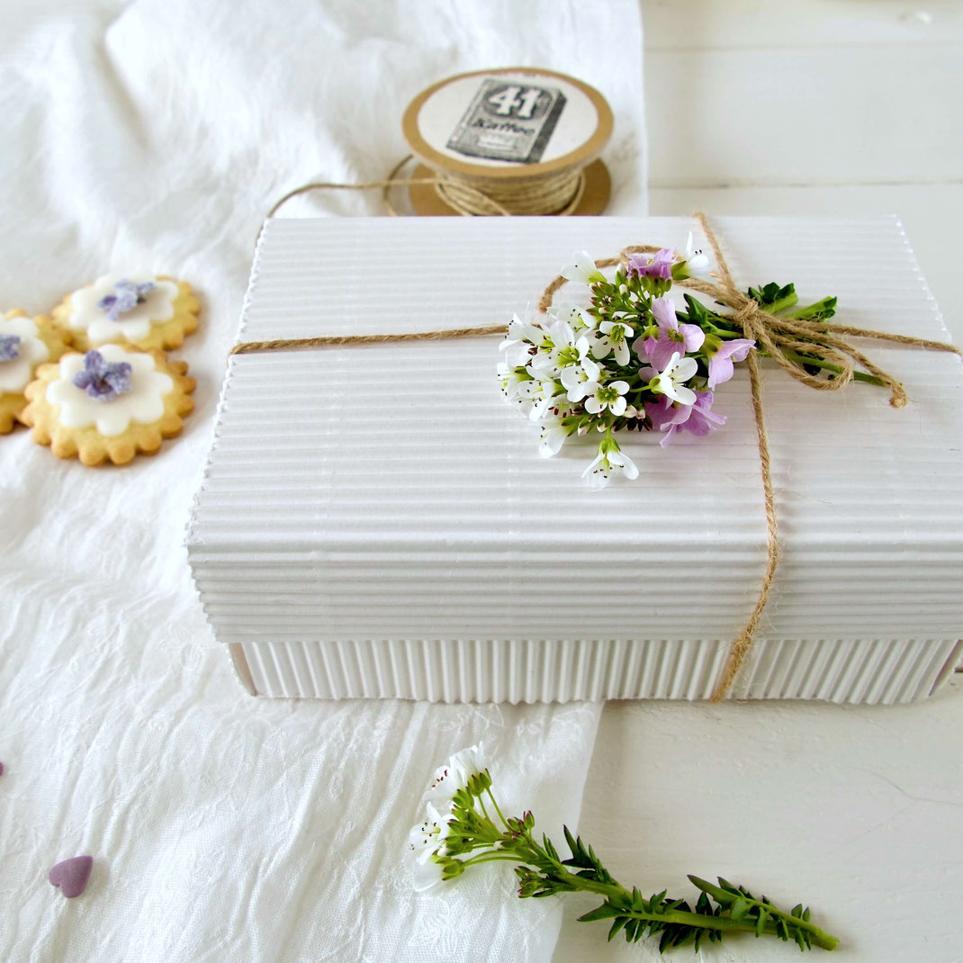 Weisse Geschenkbox aus Wellpappe mit Blumen verziert
