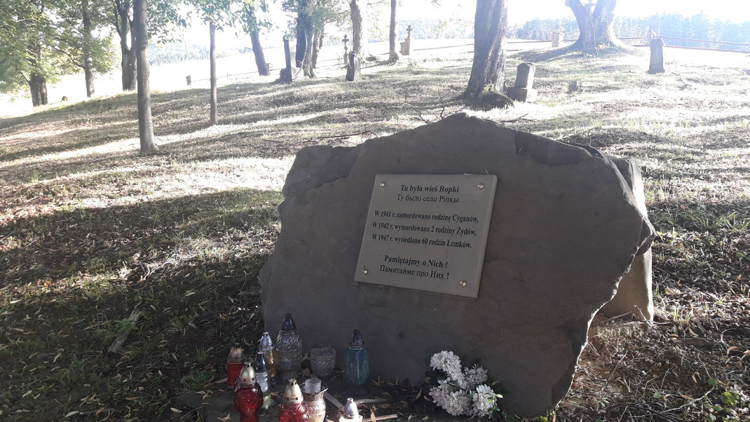 Übersetzung der Gedenktafel: "Hier stand das Dorf Ropki. 1941 wurde ein Zigeuner, 1942 zwei Juden ermordet, 1947 wurden 60 lemkische Familien vertrieben. Wir vergessen nie!"