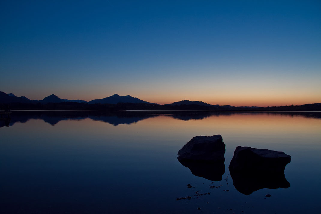 allgäu, süddeutschland, seeufer, hopfensee, sonnenuntergang, dämmerung, blaue stunde, felsen, berge, steine, spiegelung