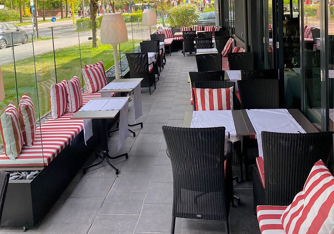 Elegante Terrasse im Sommer vor einem Restaurant mit einem Windschutz