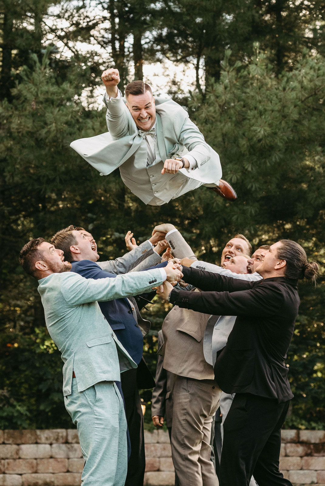 Gruppenfotos: Bräutigam wird von Freunden in die Luft geworfen und machte eine Super-Man-Pose.