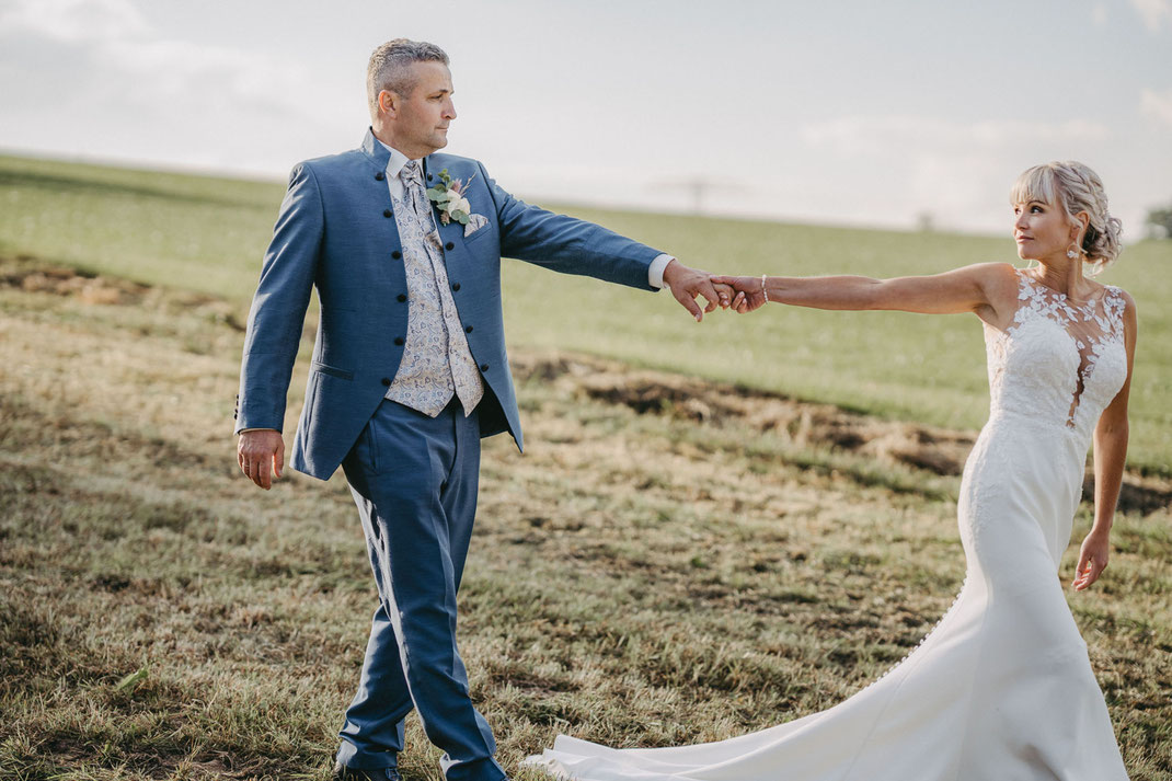 Hochzeitspaar läuft auf der Wiese und hält sich an der Hand