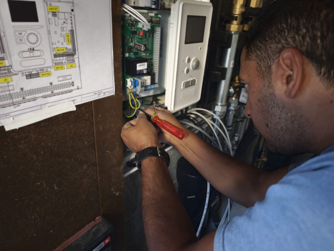 Elektriker arbeitet an einer Steuerung und Verkabelung in einem Technikraum