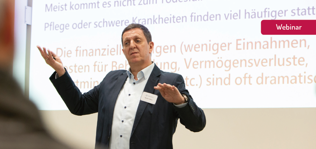 Referent gestikuliert vor Präsentationsfolie während Webinar „KI in Ihrer Praxis“