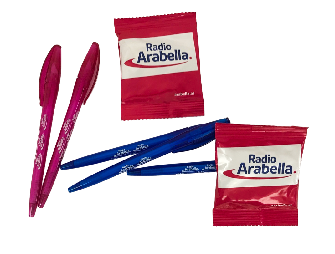 Foto von mehreren Werbemitteln für Radio Arabella, zwei rosane Kugelschreiber, drei blaue Kugelschreiber, zwei Gummibärchenpackungen, alle Artikel mit Logo personalisiert