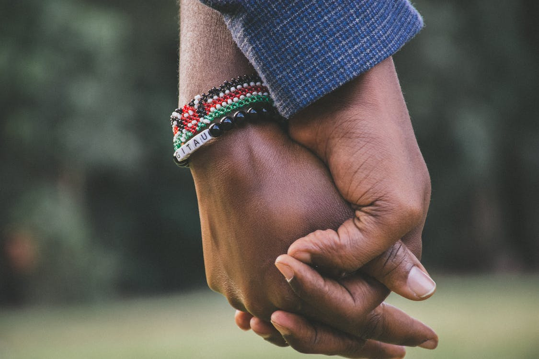 Two people holding hands in an open area.