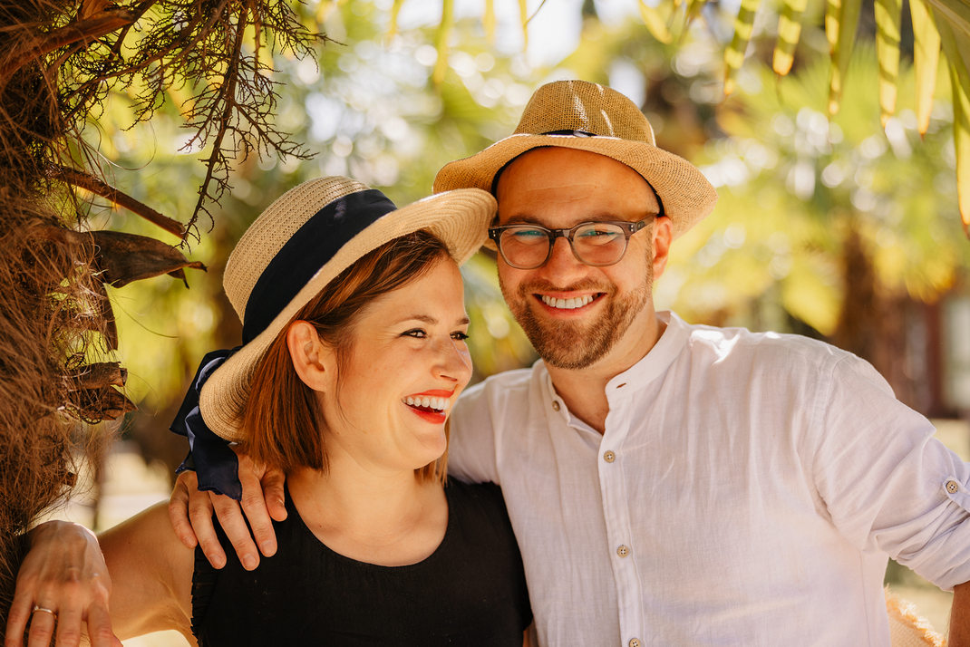 lächelndes paar lehnt glücklich unter einer palme im frankfurter palmengarten im sommer