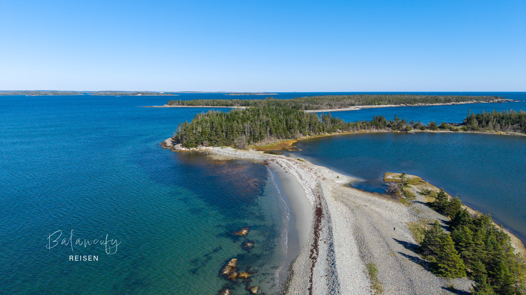 Weißer Sandstrand von Taylors Head in Nova Scotia mit Küste und klarem Wasser.