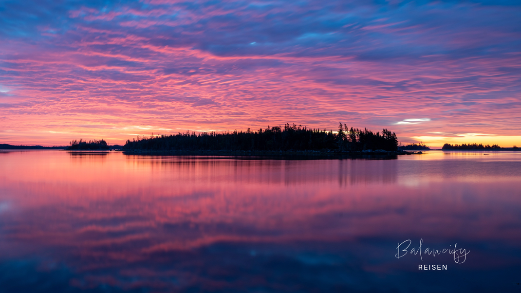 Sonnenaufgang in Moser River, Nova Scotia, mit rosarotem Himmel über dem Wasser.