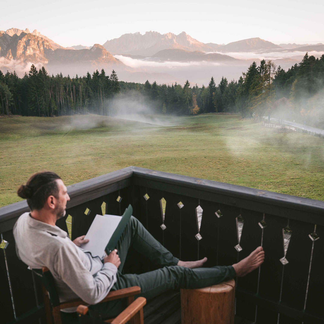 Man sitting on a balcony at Hotel Tann on the Ritten plateau in South Tyrol, enjoying the evening atmosphere with views of the Dolomites.
