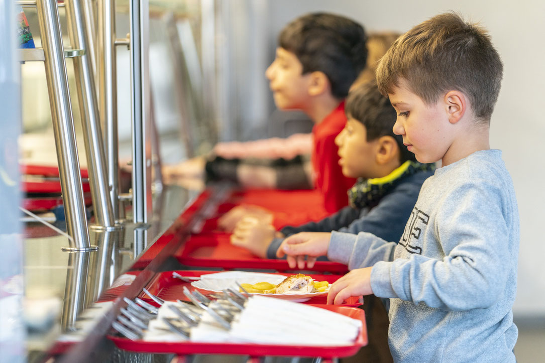 Kinder stehen bei der Essensausgabe an