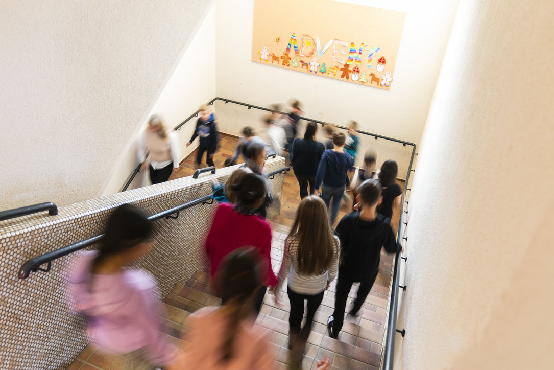 Kinder laufen die Treppen im Schulhaus herunter