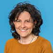 Portrait einer lächelnden Claudia Cairone vor blauem Hintergrund