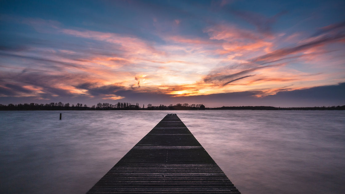 Langzeitbelichtung vom Pier Valkenburgse Meer in Valkenburg in den Niederlanden bei Sonnnuntergang