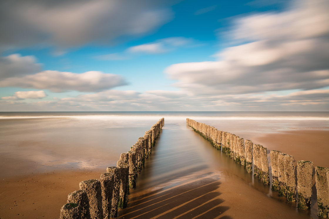 Langzeitbelichtung von Buhnen in Domburg in Zeeland in den Niederlanden bei tiefstehender Sonne