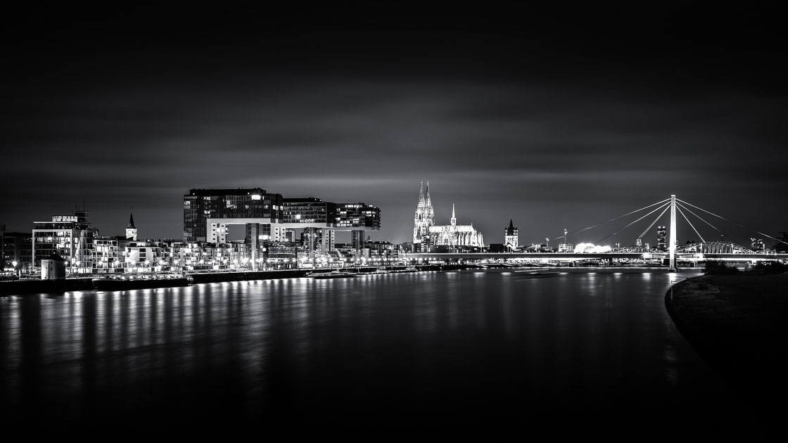 Skyline von Köln bei Nacht in schwarz-weiß mit Kranhäusern und Kölner Dom 