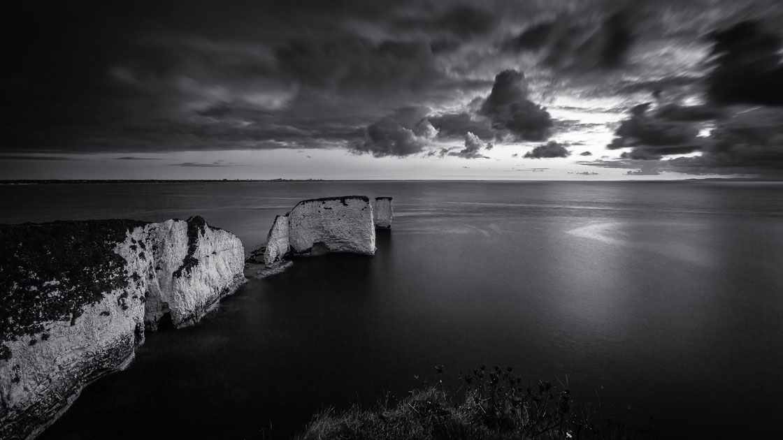 Ein frühmorgendliches Landschaftsfoto der Old Harry Rocks bei Sonnenaufgang auf der Isle of Purbeck in Dorset in England in schwarz-weiß