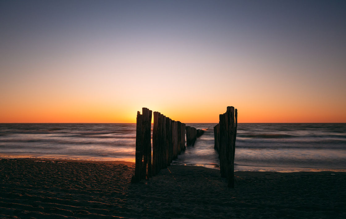 Langzeitbelichtung von Buhnen in Burgh-Haamstede in Zeeland in den Niederlanden bei Sonnenuntergang