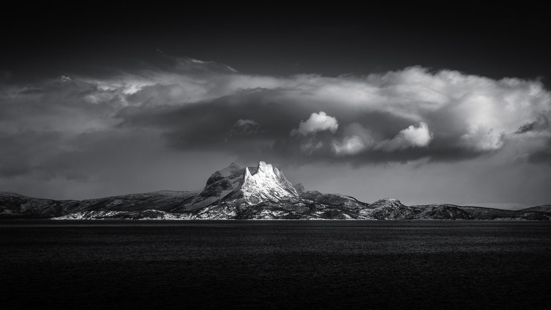 Die verschneiten Lofoten in Norwegen im Winter mit Gipfel in den Wolken in schwarz-weiß